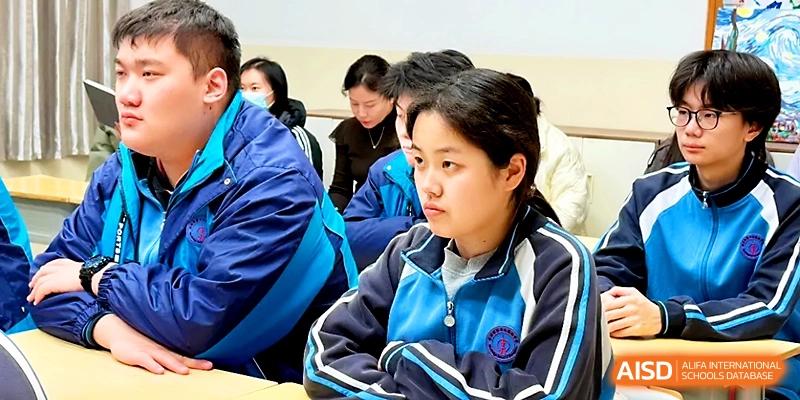 A close-up of a female student in a blue and white uniform listening intently during a group lecture at Zhengzhou No.19 High School.