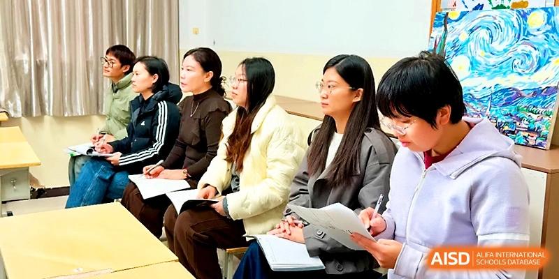 Several women sit in a row taking notes and participating in an educational workshop or meeting at Zhengzhou No.19 High School.