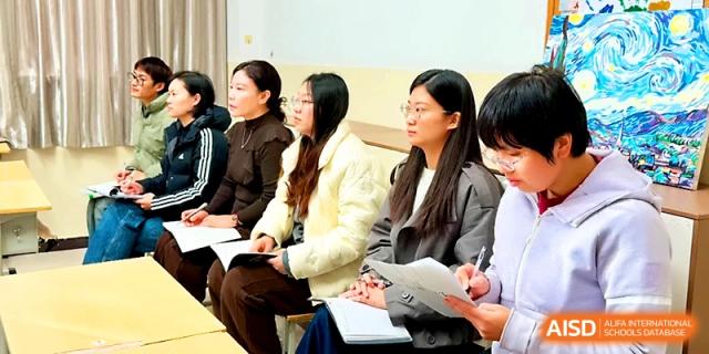 Several women sit in a row taking notes and participating in an educational workshop or meeting at Zhengzhou No.19 High School.