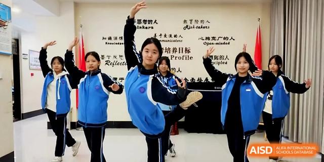 A student in a blue track suit practices a graceful traditional dance pose in a school hallway at Zhengzhou No.19 High School.