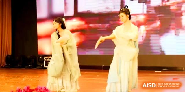 Two performers dressed in elegant, ancient-style Chinese hanfu costumes dance gracefully on stage at Zhengzhou No.19 High School.