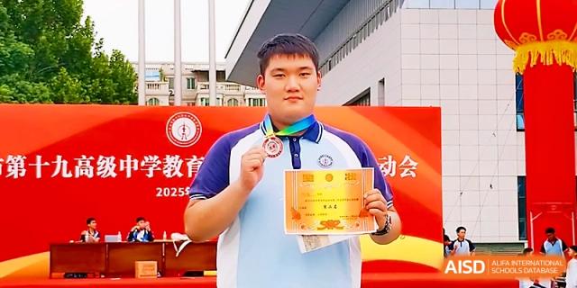 A male student proudly displays his gold medal and award certificate following a successful sports competition at Zhengzhou No.19 High School.