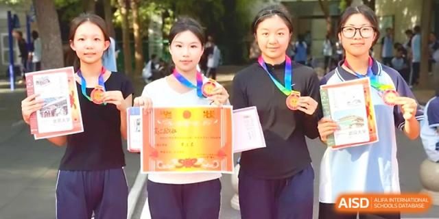 Two female students smile while showing off their medals and certificates earned during a school ceremony at Zhengzhou No.19 High School.