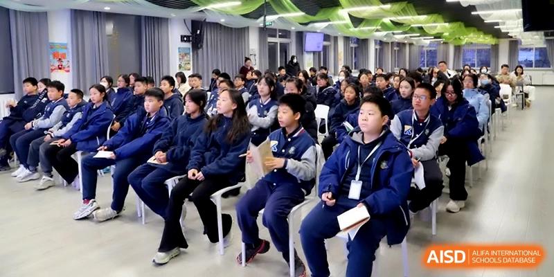 Rows of students in blue uniforms sitting and listening attentively during a school assembly at Beijing Financial Street Runze School