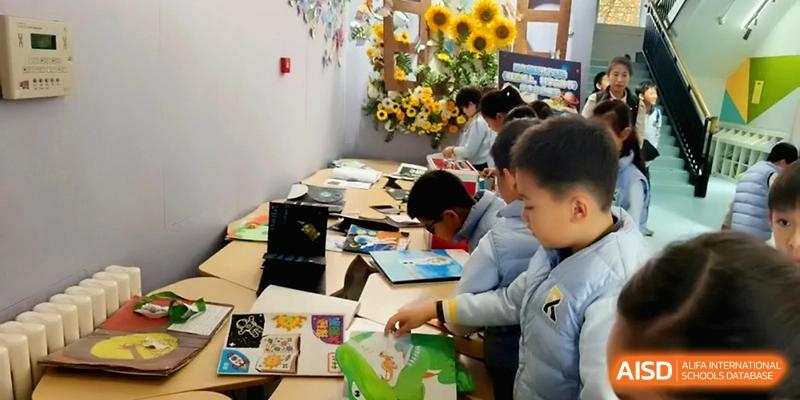 Students working together on colorful art projects at a long table in a bright room at Beijing Financial Street Runze School