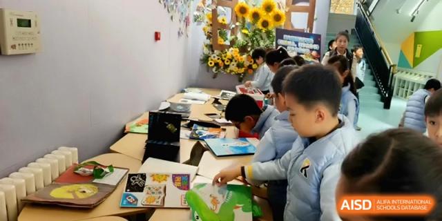 Students working together on colorful art projects at a long table in a bright room at Beijing Financial Street Runze School
