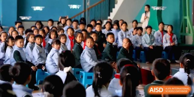 A large group of young students sitting together and looking forward during a school event at Beijing Financial Street Runze School.