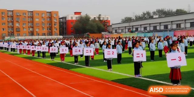 Students standing in rows on a red running track during an outdoor assembly at Beijing Financial Street Runze School.