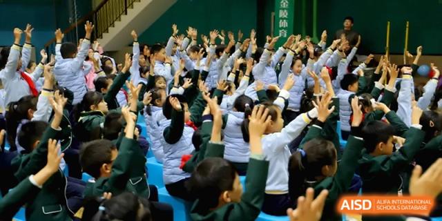 Students sitting on the floor raise their hands enthusiastically during a presentation at Beijing Financial Street Runze School.