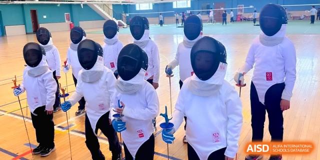 A group of students dressed in white fencing gear and masks hold their foils at Beijing Financial Street Runze School.