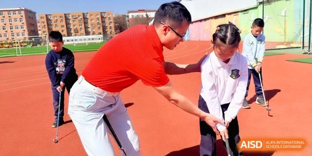 A coach assists a student with their posture on the outdoor track during sports training at Beijing Financial Street Runze School.