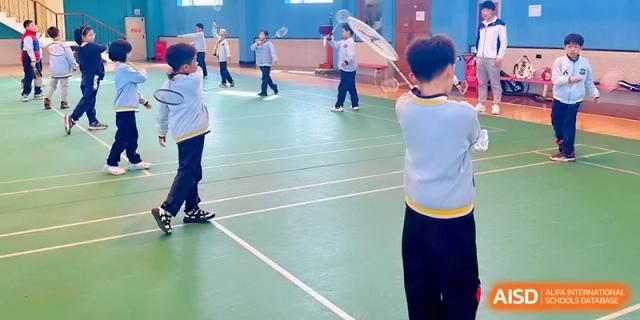 Students playing badminton on an indoor court during a physical education session at Beijing Financial Street Runze School.