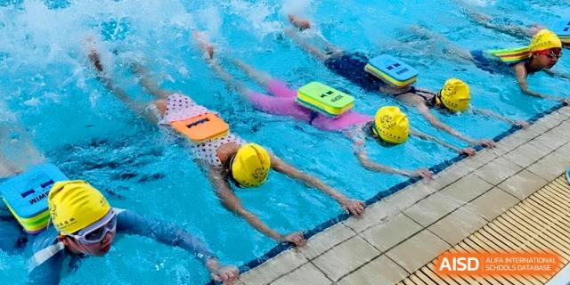 Students with floatation boards practice their swimming strokes in an indoor pool at Beijing Financial Street Runze School.