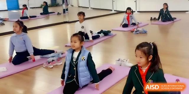 Students practicing yoga and stretching on purple mats in a bright indoor studio at Beijing Financial Street Runze School.