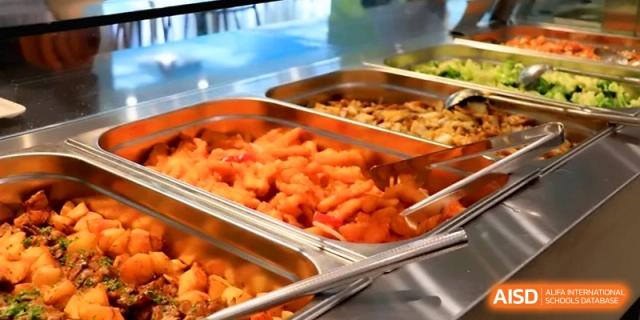 A close-up of healthy, catered food served in metal trays for student lunch at Beijing Financial Street Runze School.