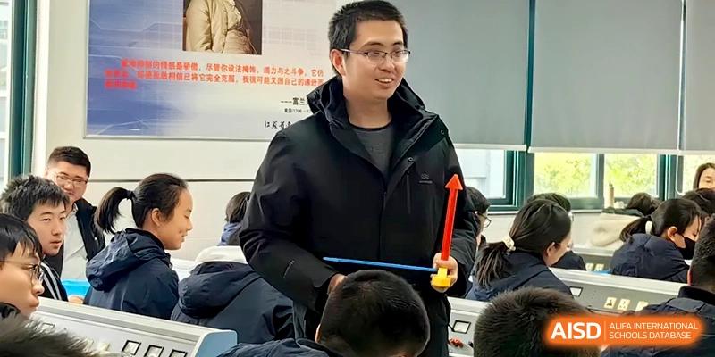 A smiling male teacher stands at the front of the classroom holding an educational model for a science demo at Changzhou Senior High School of Jiangsu Province.