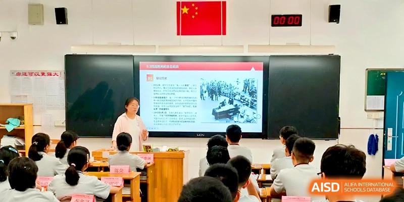 A female educator stands by a large digital screen presenting a multimedia lesson to her students at Changzhou Senior High School of Jiangsu Province.
