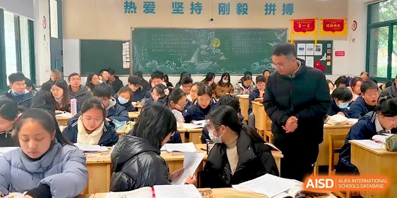Students in a classroom collaborate on an assignment while a teacher walks by a chalkboard in the back at Changzhou Senior High School of Jiangsu Province.