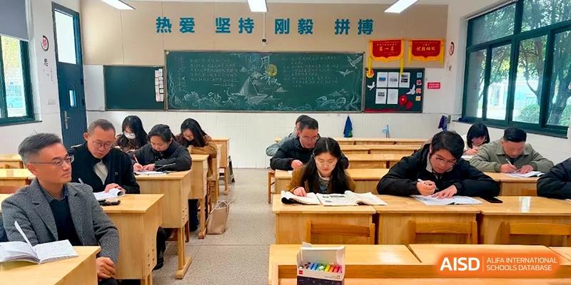 Students and teachers working together in a classroom with a green chalkboard in the background at Changzhou Senior High School of Jiangsu Province.