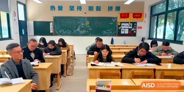 Students and teachers working together in a classroom with a green chalkboard in the background at Changzhou Senior High School of Jiangsu Province.