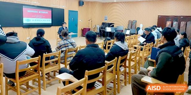 An educator leads a seminar for a group of adults seated in wooden chairs in a hall at Changzhou Senior High School of Jiangsu Province.