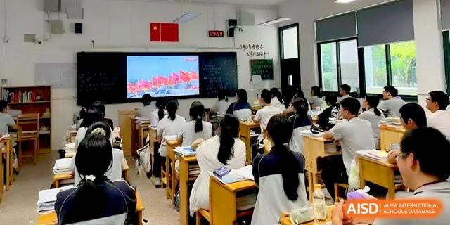 Students in white uniforms watch a multimedia presentation on a large screen in a classroom at Changzhou Senior High School of Jiangsu Province.