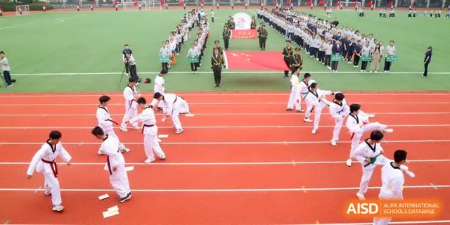 Students in white martial arts uniforms perform a synchronized routine on the red track at Changzhou Senior High School of Jiangsu Province.
