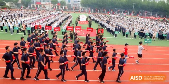 A large group of students in dark uniforms participates in a coordinated field performance at Changzhou Senior High School of Jiangsu Province.