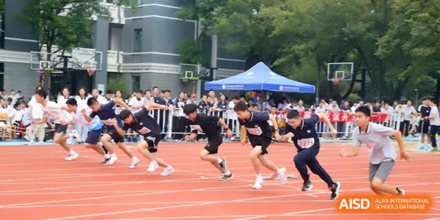 A group of male students in black uniforms lean forward at the starting blocks for a race at Changzhou Senior High School of Jiangsu Province.