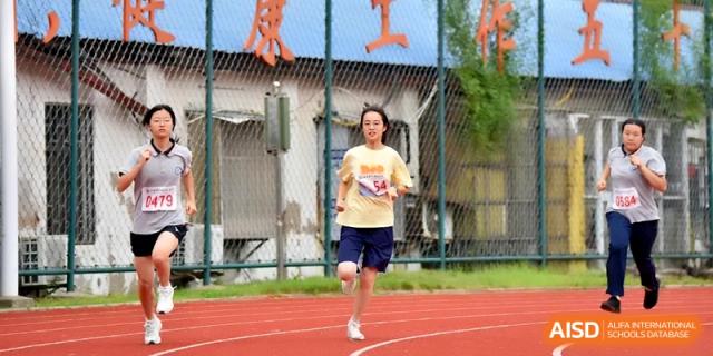 A female athlete in a yellow shirt runs toward the camera during an outdoor track competition at Changzhou Senior High School of Jiangsu Province.