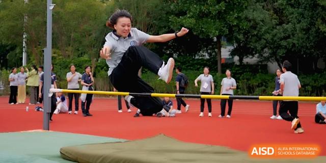 A student athlete is captured in mid-air performing a high jump over a bar on the field at Changzhou Senior High School of Jiangsu Province.