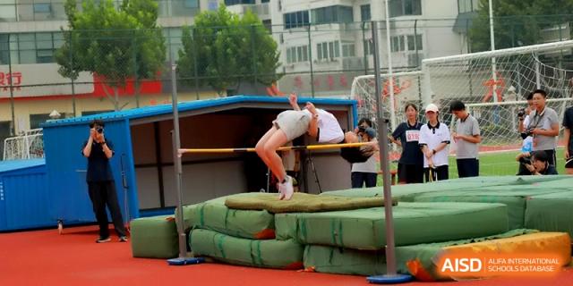 A student is seen from behind clearing the high jump bar and landing on protective mats at Changzhou Senior High School of Jiangsu Province.