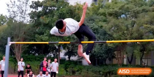 A male student in a white shirt demonstrates great form while clearing the high jump bar at Changzhou Senior High School of Jiangsu Province.