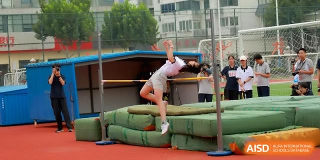A female student landing safely on green mats after a successful high jump attempt at Changzhou Senior High School of Jiangsu Province.