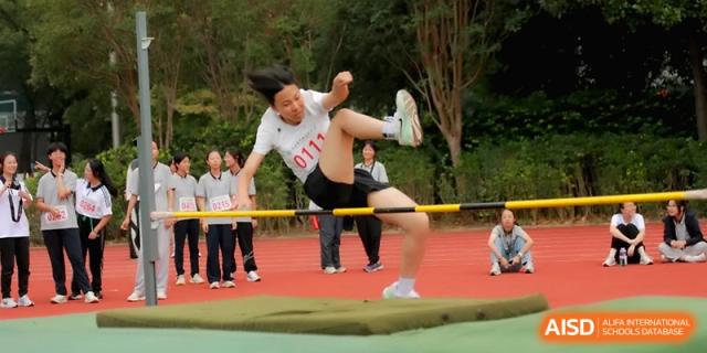 A female student in a white sports shirt focuses on her form while clearing a high jump bar at Changzhou Senior High School of Jiangsu Province.