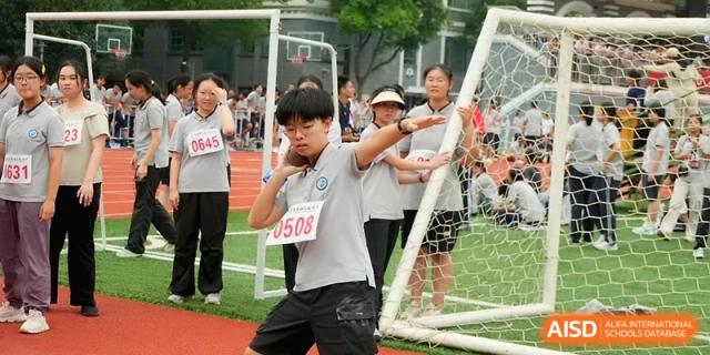 A student in a grey uniform prepares to throw a shot put during a field sports competition at Changzhou Senior High School of Jiangsu Province.