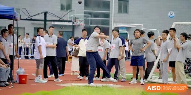 A student prepares to launch a shot put while being observed by officials and peers at Changzhou Senior High School of Jiangsu Province.