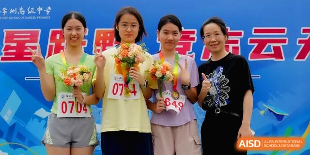 Two smiling female students pose with medals and flower bouquets after a sports victory at Changzhou Senior High School of Jiangsu Province.