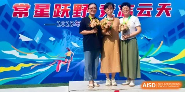 Three students stand on a podium holding flowers and wearing medals during an award ceremony at Changzhou Senior High School of Jiangsu Province.