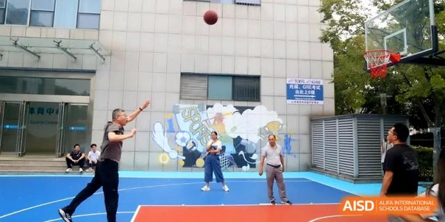 A student shoots a basketball on an outdoor court while onlookers watch the trajectory at Changzhou Senior High School of Jiangsu Province.
