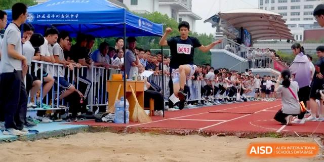 A student athlete is captured at the peak of a jump during a long jump competition at Changzhou Senior High School of Jiangsu Province.
