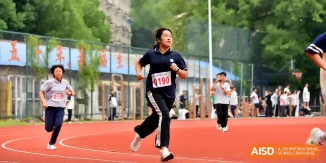 A female student in a black tracksuit runs with determination during a track and field event at Changzhou Senior High School of Jiangsu Province.