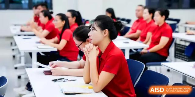 Attendees in red shirts listen attentively during a professional development workshop at the Beijing Haidian Foreign Language Shi Yan School Hainan Campus.