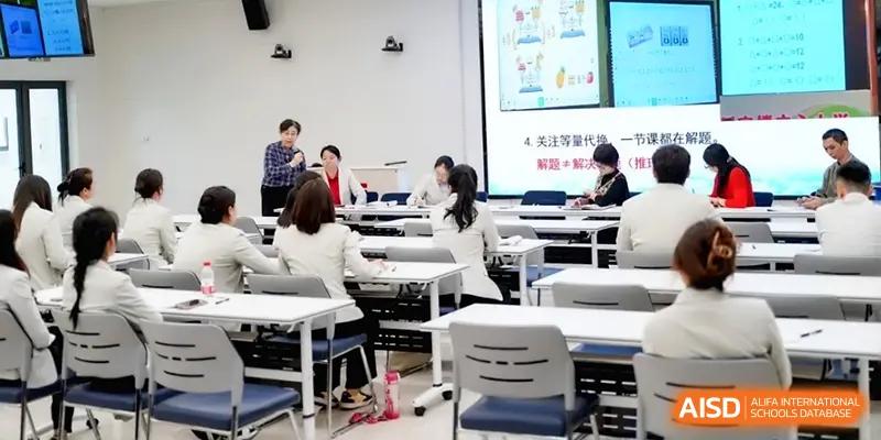 Teachers participate in a collaborative workshop in a modern, bright classroom setting at the Beijing Haidian Foreign Language Shi Yan School Hainan Campus.