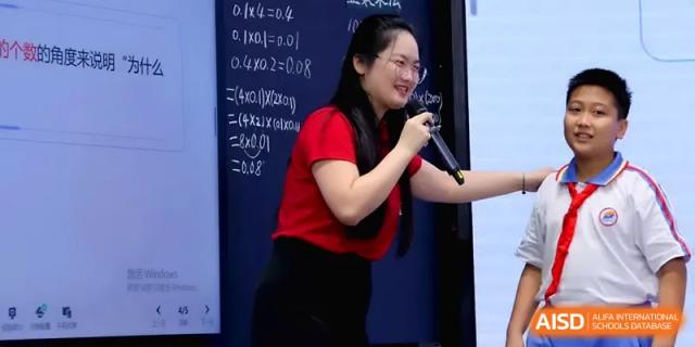 A teacher in a red shirt points to mathematical equations on a digital screen during a lecture at Beijing Haidian Foreign Language Shi Yan School Hainan Campus.
