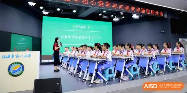 A teacher addresses a large class of students in blue and white uniforms during a math lesson at Beijing Haidian Foreign Language Shi Yan School Hainan Campus.