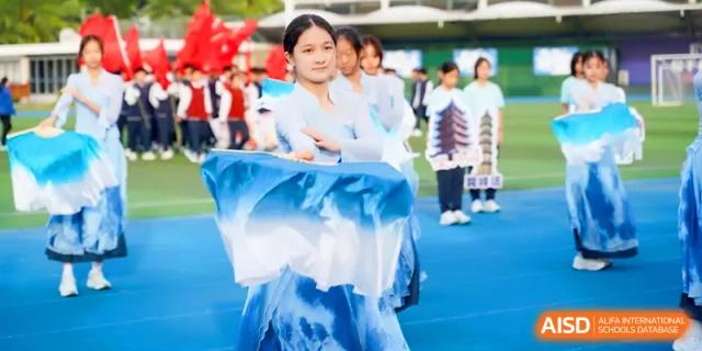 A student in a blue and white traditional dress performs a graceful dance on the field at Beijing Haidian Foreign Language Shi Yan School Hainan Campus.