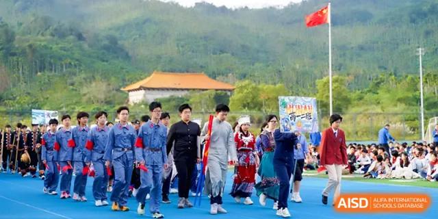 Students dressed in historical or cultural costumes march across the blue athletic track at Beijing Haidian Foreign Language Shi Yan School Hainan Campus.