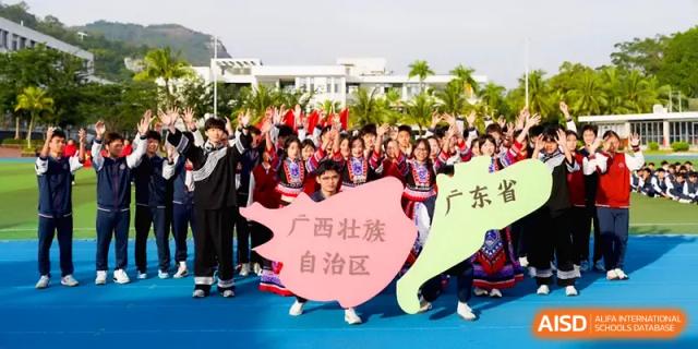 A large group of students gathers around colorful province-shaped signs during a parade at Beijing Haidian Foreign Language Shi Yan School Hainan Campus.
