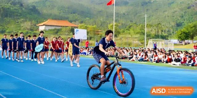 A student athlete rides a mountain bike across the blue running track during a sports meet at Beijing Haidian Foreign Language Shi Yan School Hainan Campus.